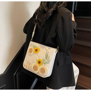 Close-up of leather bucket bag featuring sunflower embroidery and metallic hardware on strap