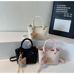 Mini bucket bags in white, black, and pink with woven texture and bear charm detail