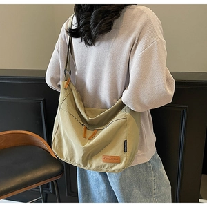 Olive green canvas messenger bag worn by model showing large capacity and drape