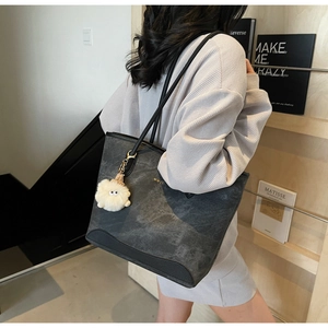 Side view of grey marble pattern tote bag with white plush charm on model's shoulder