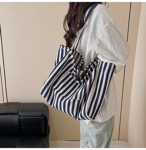 Close-up of a large blue and white striped canvas tote bag worn over the shoulder
