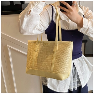 Détail du sac cabas tressé jaune clair avec bretelles et plaque logo en selfie miroir