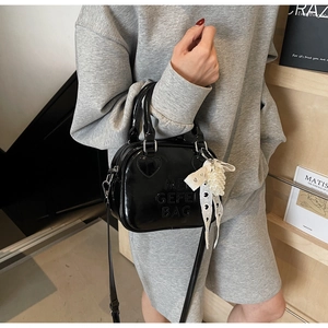 Dettaglio della mini borsa Boston in vernice nera con motivo a cuore e ciondolo di perle