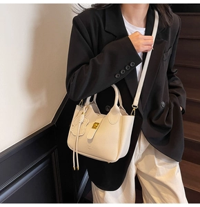 Detail showing white litchi grain leather texture and metallic clasp on crossbody bag