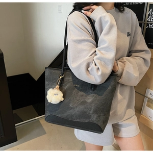 Detail of grey marble textured tote bag with black strap and white plush monster charm