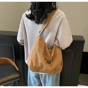 Detailed back view of a large khaki messenger bag with wide shoulder strap and leather logo