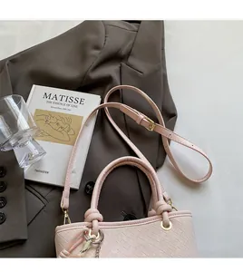 Detail view of light pink woven bucket bag with knot handle and long adjustable shoulder strap