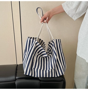 Close-up of blue and white striped canvas tote bag with outer pocket and woven handle