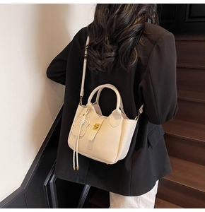 Detail of cream lychee leather tote bag with gold twist lock and bear charm