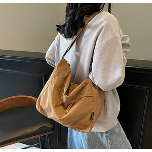 Model wearing a brown canvas messenger bag showing large capacity and drape