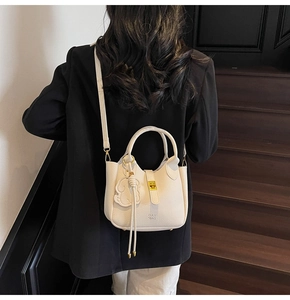 Detail of off-white lychee leather handbag with DAY BAG embossing and gold clasp