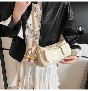 Detail of off-white glossy patent leather shoulder bag with two pockets and plush bear charm