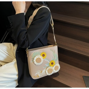 Detailed view of beige bucket bag with sunflower embroidery and wide shoulder strap