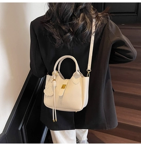 Close-up of cream pebble leather shoulder bag with gold clasp and cute dog charm