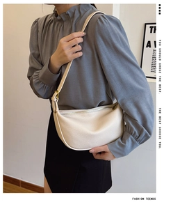 Detail of off-white crescent bag featuring lychee grain leather and adjustable strap
