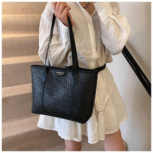 Sac fourre-tout noir à texture tressée et plaque dorée porté par un mannequin