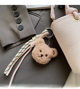 Detail of cute plush bear charm with woven strap on a pink stylish bucket bag
