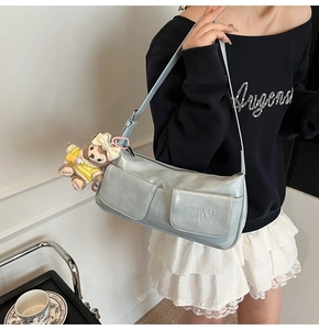 Detailed view of light blue underarm bag with double front pockets and plush bear charm