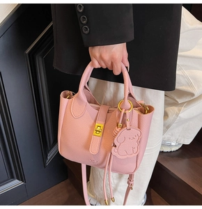 Detail of pink lychee leather bag with gold twist lock and cute dog leather charm