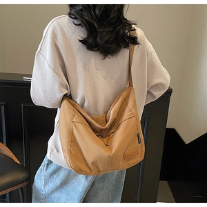 Detail of caramel canvas crossbody bag showing the CHUANGMEI brand leather patch and texture