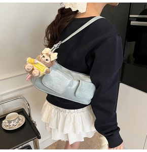 Close-up of light blue PU leather shoulder bag with pockets and cute bear charm