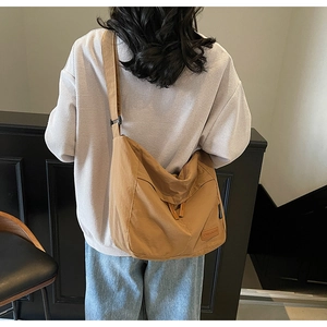 Detail of khaki canvas messenger bag featuring adjustable strap and leather brand label