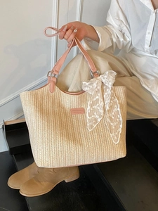 Beige woven straw tote bag with pink leather handles and delicate white lace bow detail
