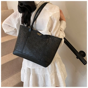 Détail du sac cabas tissé noir avec logo doré et design à bandoulière spacieux