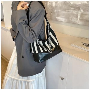 Detail of hobo bag featuring black and white vertical stripes with silver chain strap