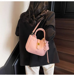 Detail showing light pink lychee texture leather bag with metal clasp and DAY BAG logo