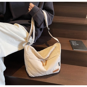 Beige large capacity canvas crossbody bag with adjustable strap and front zipper pocket