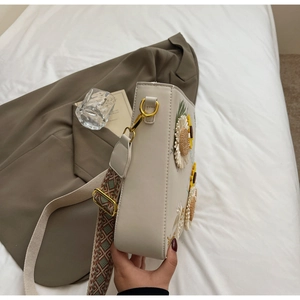 Detail of cream crossbody bag with sunflower embroidery and woven geometric strap