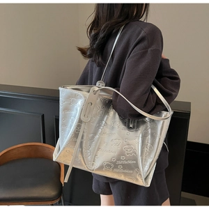 Detail van de zilveren reliëf shopper met cartoonpatronen en slanke schouderriem