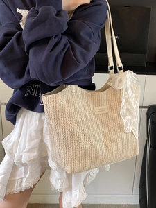 Beige woven straw tote bag with lace ribbon and leather tag on a casual model