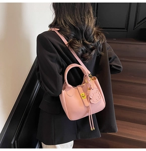 Pink lychee grain leather handbag detail with gold buckle and dog charm on stairs