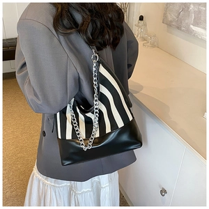 Detail of striped canvas shoulder bag with silver chain strap and leather panels