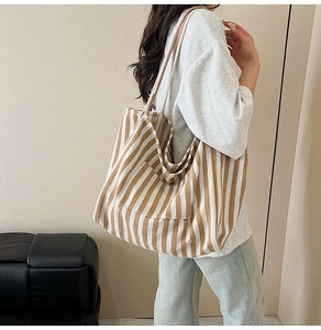 Detailed view of striped canvas tote bag showing the front pocket and sturdy strap