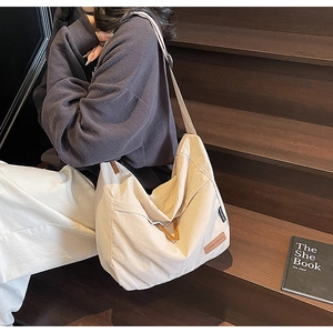 Close-up of large canvas tote bag with leather logo patch and casual shoulder strap