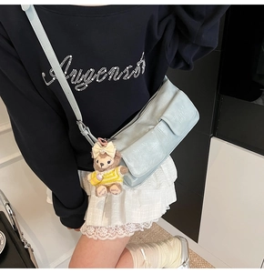 Light blue multi-pocket crossbody bag with soft texture and plush doll charm detail