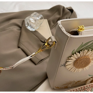 Detail of cream PU bag featuring sunflower embroidery and jacquard shoulder strap