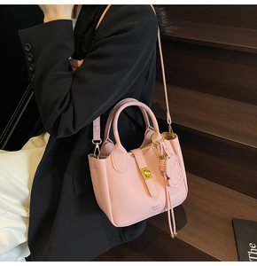 Detailed macro of pink lychee leather handbag with gold lock and DAY BAG text logo