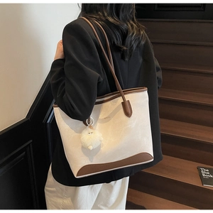 Detail of canvas tote bag with brown leather trim and cute white plush sheep charm accessory