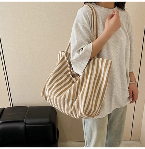 Detailed close-up of large canvas tote bag with vertical brown and white stripes and side pocket