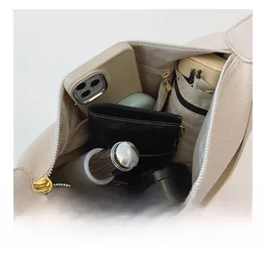 Spacious interior of off-white lychee grain leather crossbody bag showing daily essentials