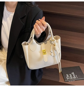 Detail of off-white lychee leather handbag with gold twist lock and DAY BAG text