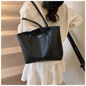 Détail de la texture tressée sur sac cabas noir avec logo doré et anses en cuir