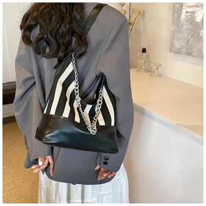 Detail of black and white striped canvas shoulder bag with silver chunky chain strap
