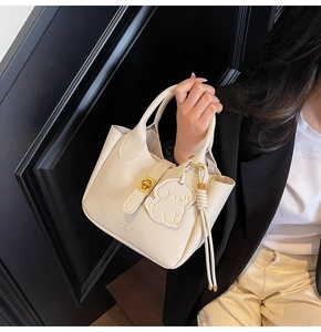 Detail of cream pebbled leather tote with gold twist lock and dog-shaped charm