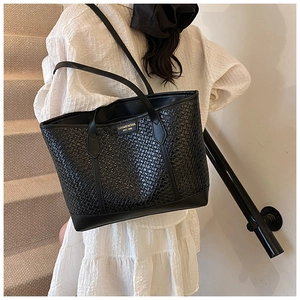 Gros plan du sac cabas noir en cuir tressé avec logo doré et détails texturés