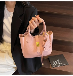 Detailed shot of pink textured leather day bag with gold clasp and dog charm
